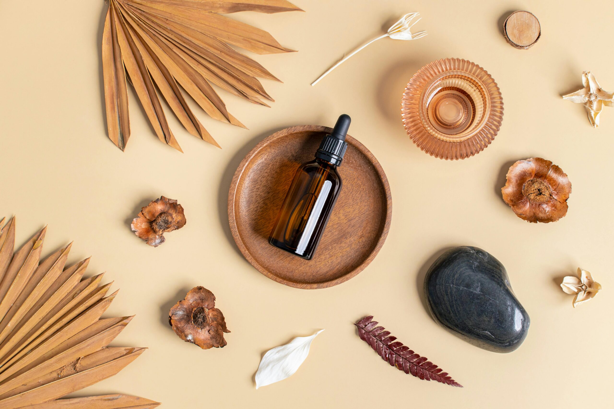 Flat lay of essential oil bottle with natural elements on a beige background, promoting wellness and relaxation.